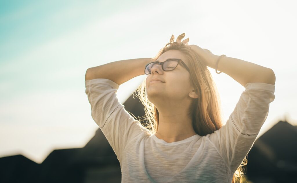 Woman filled with dopamine with hands behind head, smiling to the sky